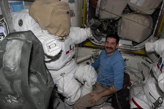 NASA image: NASA astronaut Jack Hathaway works on a spacesuit inside the Quest airlock