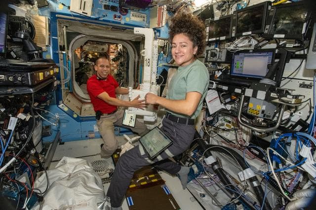 NASA image: NASA astronauts Chris Williams and Jessica Meir inspect and configure a spacesuit jetpack