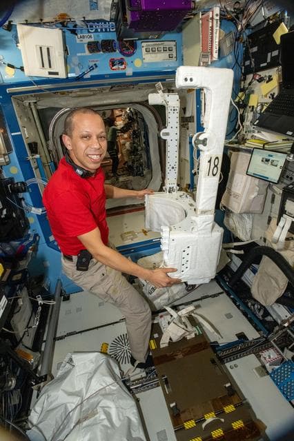NASA image: NASA astronaut Chris Williams inspects and configures a spacesuit jetpack