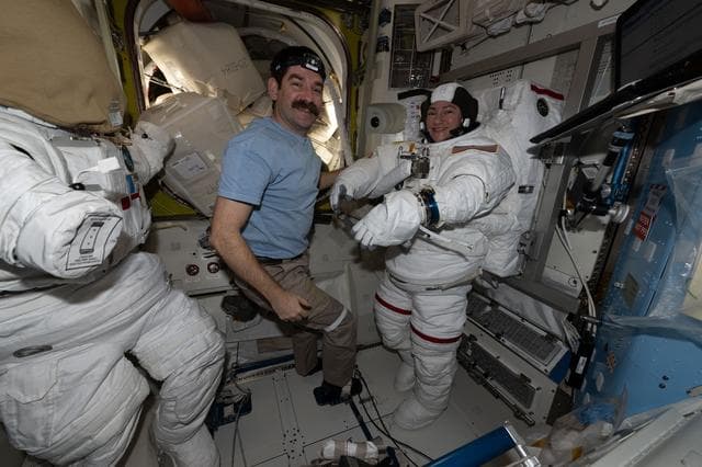 NASA image: NASA astronaut Jack Hathaway assists NASA astronaut Jessica Meir as she tries on a spacesuit