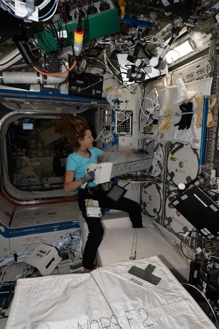 NASA image: ESA astronaut Sophie Adenot inserts biological research samples into a science freezer