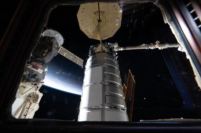 NASA image: Two spacecraft attached to the International Space Station are seen through a window in the cupola