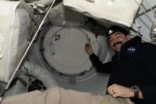NASA astronaut Jack Hathathe way prepares to open SpaceX Dragon cargo spacecraft's hatch