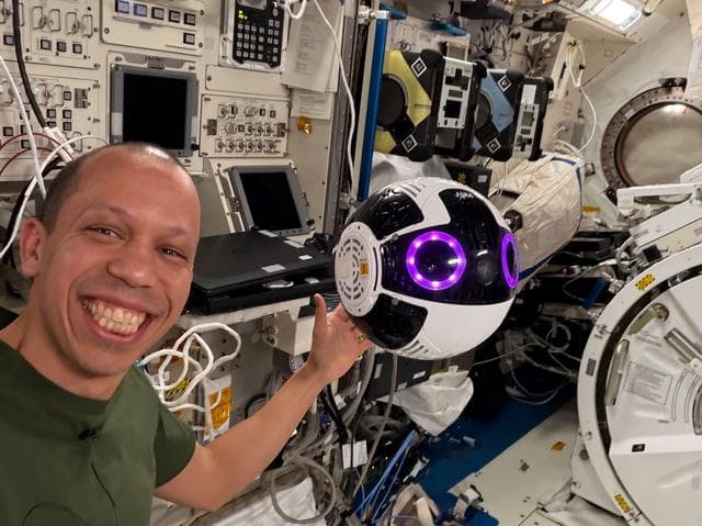 NASA image: NASA astronaut Chris Williams poses with a free‑flying robotic camera 
