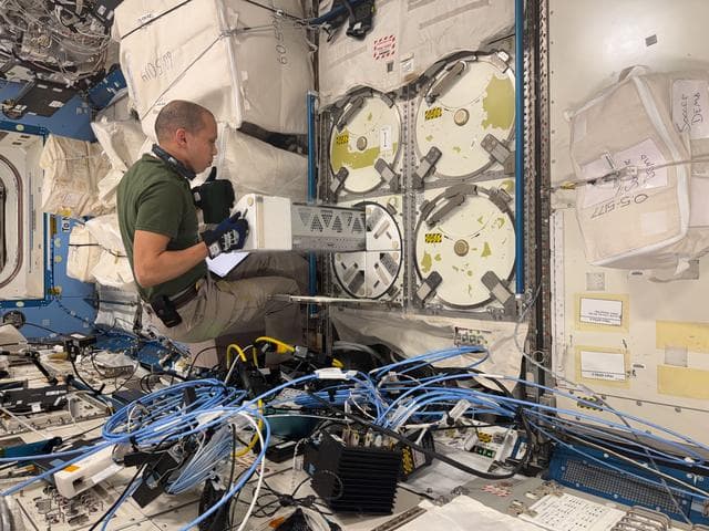 NASA image: NASA astronaut Chris Williams inserts a cryogenic storage unit into a science freezer