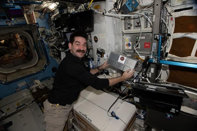 NASA image: NASA astronaut Jack Hathaway installs research hardware inside a Powered Ascent Utility Locker