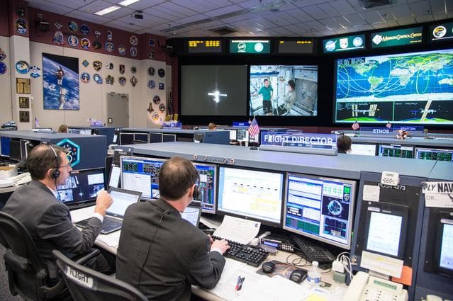 NASA image: Date: 03-11-15.Location: Bldg 30, FCR-1.Subject:  Expedition 42 flight controllers on console in FCR-1 during the undocking of Expedition 42 crew (Samokutyaev, Wilmore, Serova) on the Soyuz TMA-14M spacecraft from the Poisk module on ISS.Photographer: James Blair