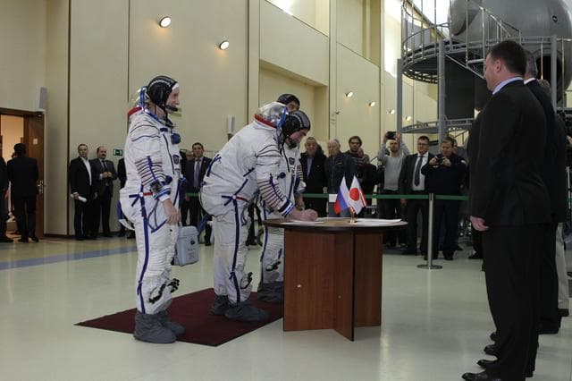 NASA image: At the Gagarin Cosmonaut Training Center in Star City, Russia, Expedition 46-47 backup crewmember Anatoly Ivanishin of the Russian Federal Space Agency (Roscosmos) signs in Nov. 19 for the start of qualification exams as his crewmates, Kate Rubins of NASA (left) and Takuya Onishi of the Japan Aerospace Exploration Agency (right, behind Ivanishin) look on. They are the backups to the prime crewmembers, Yuri Malenchenko of Roscosmos, Tim Kopra of NASA and Tim Peake of the European Space Agency, who will launch Dec. 15 in the Soyuz TMA-19M spacecraft from the Baikonur Cosmodrome in Kazakhstan for a six-month mission on the International Space Station..NASA/Seth Marcantel
