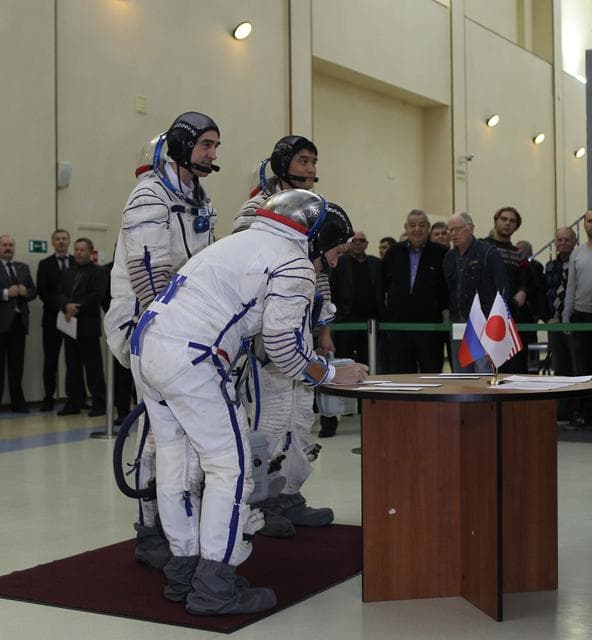 NASA image: At the Gagarin Cosmonaut Training Center in Star City, Russia, Expedition 46-47 backup crewmember Kate Rubins of NASA signs in Nov. 19 for the start of qualification exams as her crewmates, Anatoly Ivanishin of the Russian Federal Space Agency (Roscosmos) and Takuya Onishi of the Japan Aerospace Exploration Agency look on. They are the backups to the prime crewmembers, Yuri Malenchenko of Roscosmos, Tim Kopra of NASA and Tim Peake of the European Space Agency, who will launch Dec. 15 in the Soyuz TMA-19M spacecraft from the Baikonur Cosmodrome in Kazakhstan for a six-month mission on the International Space Station..NASA/Seth Marcantel
