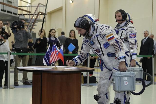 NASA image: At the Gagarin Cosmonaut Training Center in Star City, Russia, Expedition 46-47 crewmember Yuri Malenchenko of the Russian Federal Space Agency (Roscosmos) signs in for his qualification exam Nov. 20 as his crewmate, Tim Peake of the European Space Agency looks on. Along with Tim Kopra of NASA, Malenchenko and Peake will launch Dec. 15 on their Soyuz TMA-19M spacecraft Dec. 15 from the Baikonur Cosmodrome in Kazakhstan for a six-month mission on the International Space Station..NASA/Seth Marcantel