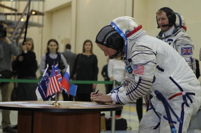 NASA image: At the Gagarin Cosmonaut Training Center in Star City, Russia, Expedition 46-47 crewmember Tim Kopra of NASA signs in for his qualification exam Nov. 20 as his crewmate, Tim Peake of the European Space Agency looks on. Along with Yuri Malenchenko of the Russian Federal Space Agency (Roscosmos), Kopra and Peake will launch Dec. 15 on their Soyuz TMA-19M spacecraft Dec. 15 from the Baikonur Cosmodrome in Kazakhstan for a six-month mission on the International Space Station..NASA/Seth Marcantel