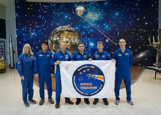 NASA image: During a break from training, the Expedition 46-47 prime and backup crewmembers toured the Korolev Museum at the Baikonur Cosmodrome in Kazakhstan Dec. 10 and displayed a flag bearing the logo for the prime crew���s Soyuz mission. From left to right are backup crewmembers Kate Rubins of NASA and Takuya Onishi of the Japan Aerospace Exploration Agency, prime crewmembers Tim Kopra of NASA,  Yuri Malenchenko of the Russian Federal Space Agency (Roscosmos) and Tim Peake of the European Space Agency who are holding the flag, and backup crewmember Anatoly Ivanishin of Roscosmos. Kopra, Peake and Malenchenko will launch Dec. 15 on the Soyuz TMA-19M spacecraft for a six-month mission on the International Space Station...NASA/Victor Zelentsov.