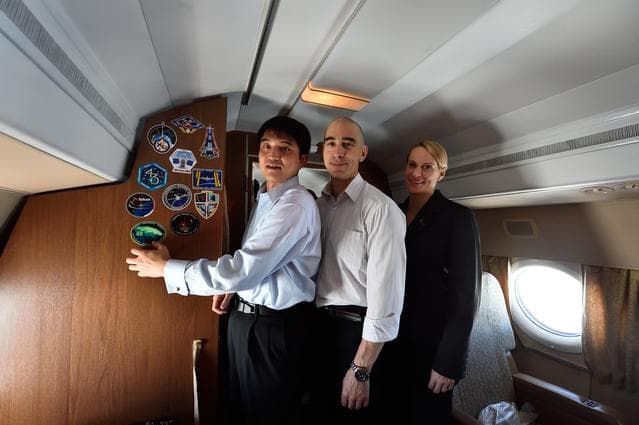 NASA image: Aboard their aircraft on route to their launch site in Baikonur, Kazakhstan, ISS Expedition 48-49 crewmembers Takuya Onishi of the Japan Aerospace Exploration Agency (left), Anatoly Ivanishin of Roscosmos (center) and Kate Rubins of NASA (right) affix their mission insignia sticker to the wall June 24 after departing their training base in Star City, Russia. The trio will launch July 7 from the Baikonur Cosmodrome in Kazakhstan on the Soyuz MS-01 spacecraft for a planned four-month mission on the International Space Station...NASA/Alexander Vysotsky.