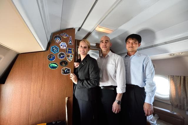 NASA image: Aboard their aircraft en route to their launch site in Baikonur, Kazakhstan, ISS Expedition 48-49 crewmembers Kate Rubins of NASA (left), Anatoly Ivanishin of Roscosmos (center) and Takuya Onishi of the Japan Aerospace Exploration Agency (right) pose for pictures after affixing their mission insignia stickers to the wall June 24 following their departure from their training base in Star City, Russia. The trio will launch July 7 from the Baikonur Cosmodrome in Kazakhstan on the Soyuz MS-01 spacecraft for a planned four-month mission on the International Space Station...NASA/Alexander Vysotsky.