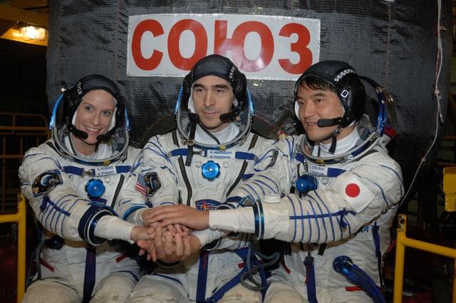 NASA image: In the Integration Facility at the Baikonur Cosmodrome in Kazakhstan, Expedition 48-49 crewmembers Kate Rubins of NASA (left), Anatoly Ivanishin of Roscosmos (center) and Takuya Onishi of the Japan Aerospace Exploration Agency (right) pose for pictures June 25 in front of the Soyuz MS-01 spacecraft during a �ޔfit check��� dress rehearsal activity. The trio will launch on July 7, Baikonur time, on the Soyuz MS-01 for a planned four-month mission on the International Space Station...NASA/Alexander Vysotsky.