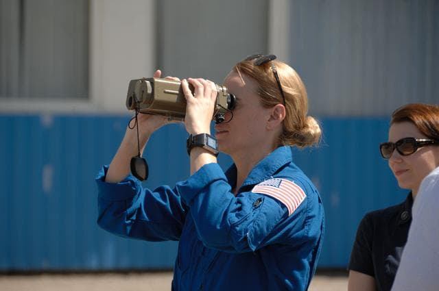 NASA image: Outside the Integration Facility at the Baikonur Cosmodrome in Kazakhstan, Expedition 48-49 crewmember Kate Rubins of NASA tries out a pair of binoculars June 25 as she prepares for launch July 7, Baikonur time, on the Soyuz MS-01 spacecraft with Takuya Onishi of the Japan Aerospace Exploration Agency and Anatoly Ivanishin of Roscosmos for a planned four-month mission on the International Space Station...NASA/Alexander Vysotsky.