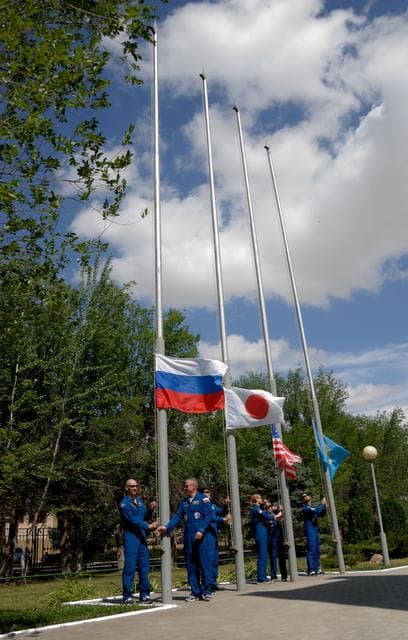 NASA image: Outside their Cosmonaut Hotel crew quarters in Baikonur, Kazakhstan, the Expedition 48-49 prime and backup crewmembers conduct the traditional raising of the Russian, Japanese, American and Kazakh flags June 26. Prime crewmembers Kate Rubins of NASA, Anatoly Ivanishin of Roscosmos and Takuya Onishi of the Japan Aerospace Exploration Agency will launch on July 7, Baikonur time, on the Soyuz MS-01 spacecraft for a planned four-month mission on the International Space Station...NASA/Alexander Vysotsky.