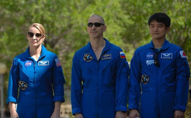 NASA image: Outside their Cosmonaut Hotel crew quarters in Baikonur, Kazakhstan, Expedition 48-49 crewmembers Kate Rubins of NASA (left), Anatoly Ivanishin of Roscosmos (center) and Takuya Onishi of the Japan Aerospace Exploration Agency (right) listen to remarks June 26 during the traditional raising of the American, Russian, Japanese and Kazakh flags. The trio will launch on July 7, Baikonur time, on the Soyuz MS-01 spacecraft for a planned four-month mission on the International Space Station...NASA/Alexander Vysotsky.