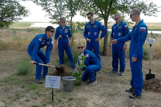 NASA image: At the Cosmonaut Hotel in Baikonur, Kazakhstan, Expedition 48-49 crewmember Takuya Onishi of the Japan Aerospace Exploration Agency (left) lends a hand to NASA���s Kate Rubins (crouching) as she plants a tree in her name June 30 in traditional pre-launch activities. Standing from left to right are backup crewmembers Peggy Whitson of NASA, Thomas Pesquet of the European Space Agency and Oleg Novitskiy of Roscosmos and prime crewmember Anatoly Ivanishin of Roscosmos. Rubins, Ivanishin and Onishi will launch July 7, Baikonur time, on the Soyuz MS-01 spacecraft for a planned four-month mission on the International Space Station...NASA/Alexander Vysotsky.