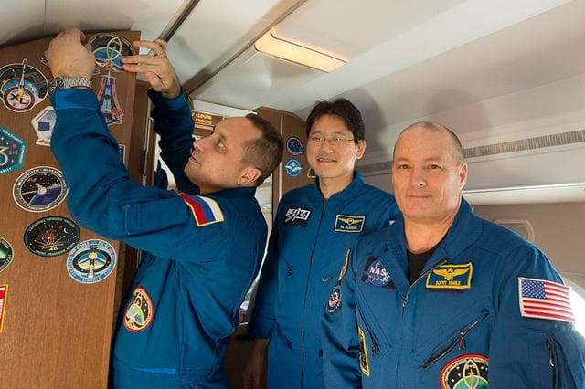 NASA image: jsc2017e136094 - Aboard a Gagarin Cosmonaut Training Center aircraft en route to the launch site at the Baikonur Cosmodrome in Kazakhstan, Expedition 54-55 crewmember Anton Shkaplerov of the Russian Federal Space Agency (Roscosmos, left) affixes a sticker