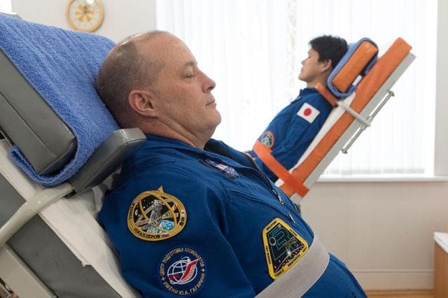 NASA image: jsc2017e137341 - At the Cosmonaut Hotel crew quarters in Baikonur, Kazakhstan, Expedition 54-55 prime crewmembers Scott Tingle of NASA (left) and Norishige Kanai of the Japan Aerospace Exploration Agency (right) test their vestibular skills on tilt tables