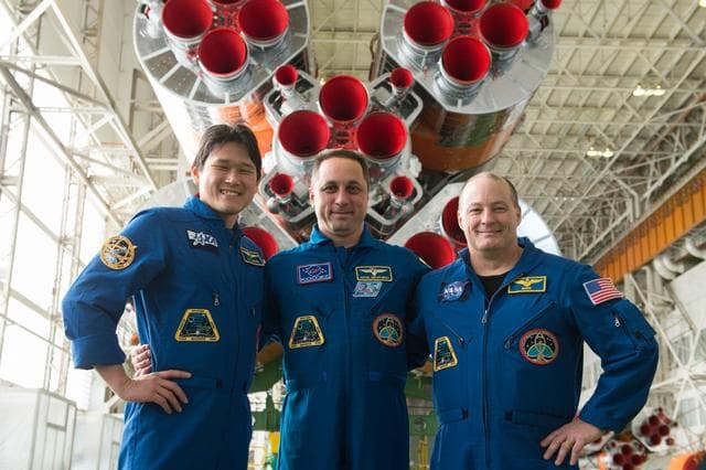 NASA image: jsc2017e138118 - In the Integration Facility at the Baikonur Cosmodrome in Kazakhstan, the Expedition 54-55 prime crewmembers pose for pictures Dec. 13 in front of the first stage of the Soyuz booster rocket. From left to right are Norishige Kanai of the 