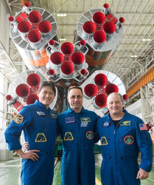 NASA image: jsc2017e138119 - In the Integration Facility at the Baikonur Cosmodrome in Kazakhstan, the Expedition 54-55 prime crewmembers pose for pictures Dec. 13 in front of the first stage of the Soyuz booster rocket. From left to right are Norishige Kanai of the 