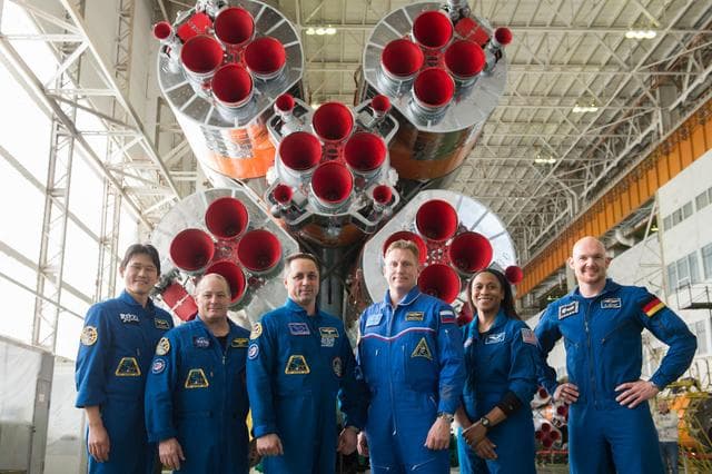 NASA image: jsc2017e138124 - In the Integration Facility at the Baikonur Cosmodrome in Kazakhstan, the Expedition 54-55 prime and backup crewmembers pose for pictures Dec. 13 in front of the first stage of the Soyuz booster rocket. From left to right are prime crewme