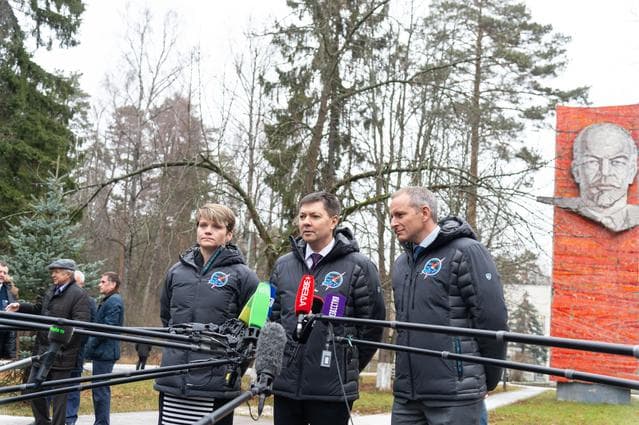 NASA image: jsc2018e097267 - With the statue of Vladimir Lenin serving as a backdrop, Expedition 58 crewmembers Anne McClain of NASA (left), Oleg Kononenko of Roscosmos (center) and David Saint-Jacques of the Canadian Space Agency (right) answer reporters’ question