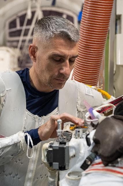 NASA astronaut Luke Delaney practices suiting up in a spacesuit