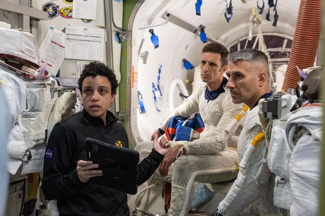 NASA image: Astronaut Jessica Watkins assists astronauts Josh Kutryk and Luke Delaney as they practice suiting up in spacesuits