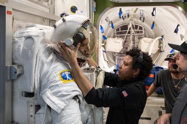 NASA image: Astronaut Jessica Watkins assists astronaut Josh Kutryk as he practices suiting up in a spacesuit