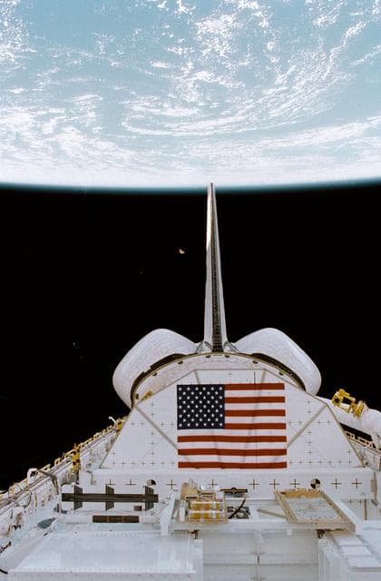 NASA image: PLB, vertical tail, OMS pods above Earth with moon in distant background