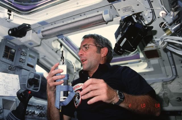 NASA image: Commander Truly on aft flight deck holding communication kit assembly (ASSY)
