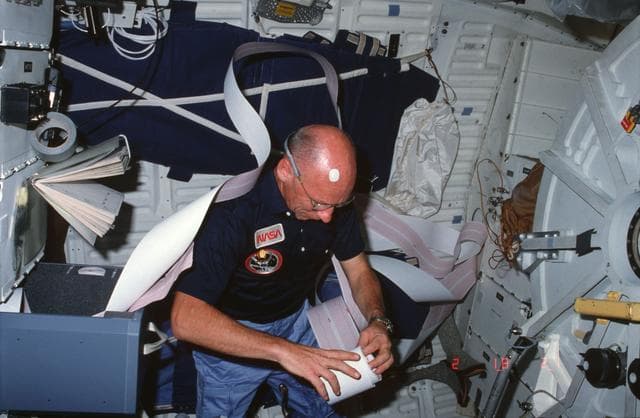 NASA image: Mission Specialist (MS) Thornton rolls DSO 404 strip chart on middeck