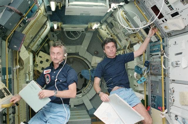 NASA image: Astronauts Garriott and Merbold monitoring experiemnts in Spacelab