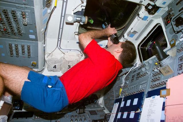 NASA image: MS Grunsfeld with binoculars on the aft flight deck