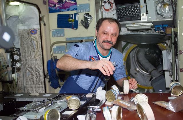 NASA image: Usachev in Service Module with Russian food cans