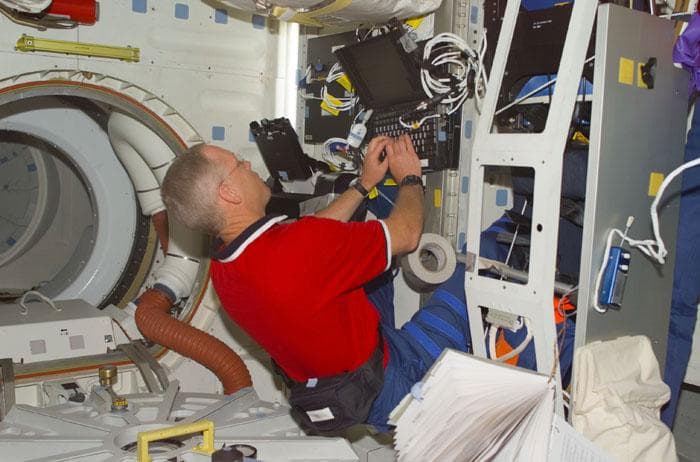 NASA image: Forrester types on laptop computer in the orbiter middeck