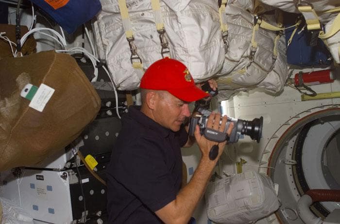 NASA image: Sturckow with baseball cap and camcorder in the orbiter middeck