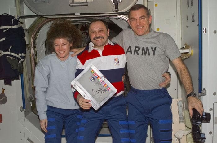 NASA image: Helms, Usachev and Voss pose with the ISS Ships Log