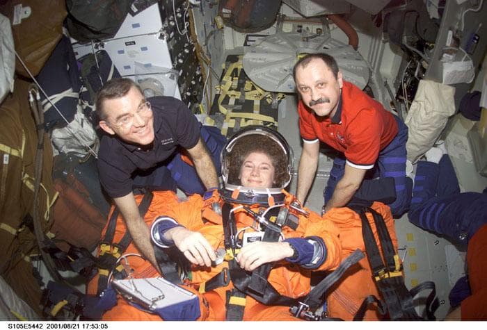 NASA image: Voss and Usachev strap Helms into a middeck seat