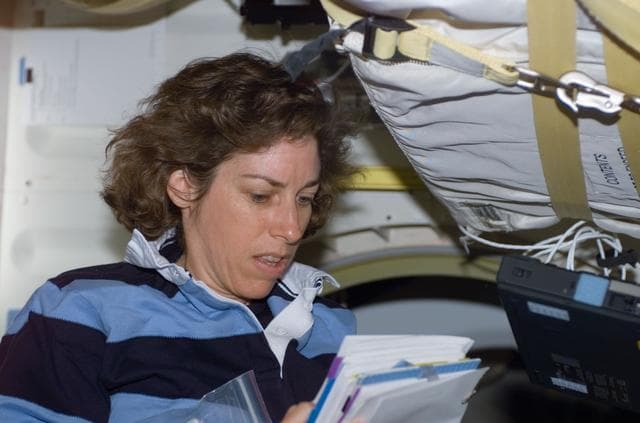 NASA image: MS Ochoa reads a notebook on the middeck of Atlantis during STS-110