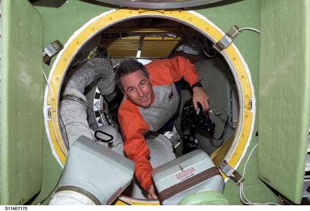 NASA image: Robinson with camera in hatch leading to FGB