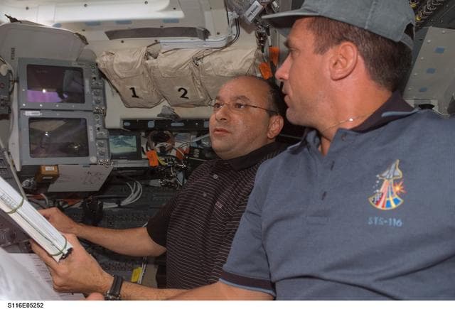 NASA image: STS-116 crewmembers Polansky and Oefelin looks over crew procedures in FD on Space Shuttle Discovery