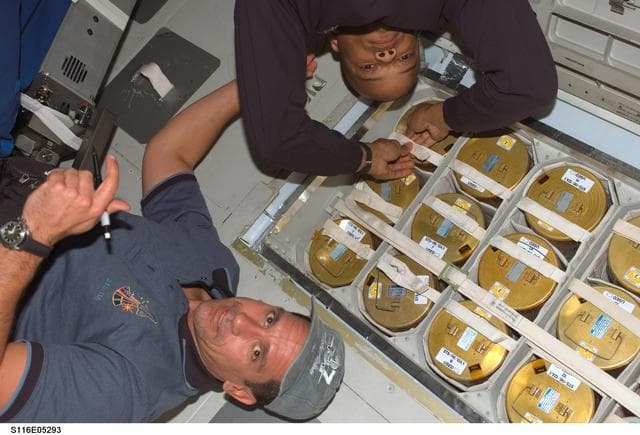 NASA image: STS-116 crewmembers Oefelin and Curbeam, Jr., work with lithium hydroxide in the MDDK on Space Shuttle Discovery