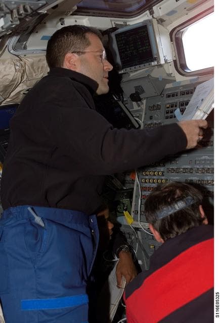 NASA image: STS-116 MS Patrick looks at crew procedures in the aft FD on Space Shuttle Discovery