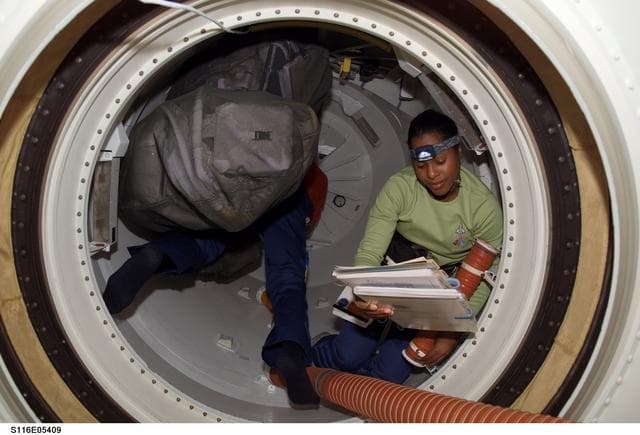 NASA image: STS-116 MS Higginbotham looks at crew procedures in the hatch area on Space Shuttle Discovery
