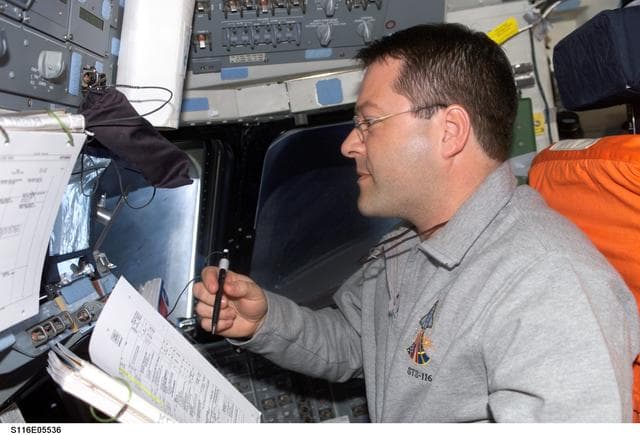 NASA image: STS-116 MS Patrick looks at crew procedures in the aft FD on Space Shuttle Discovery