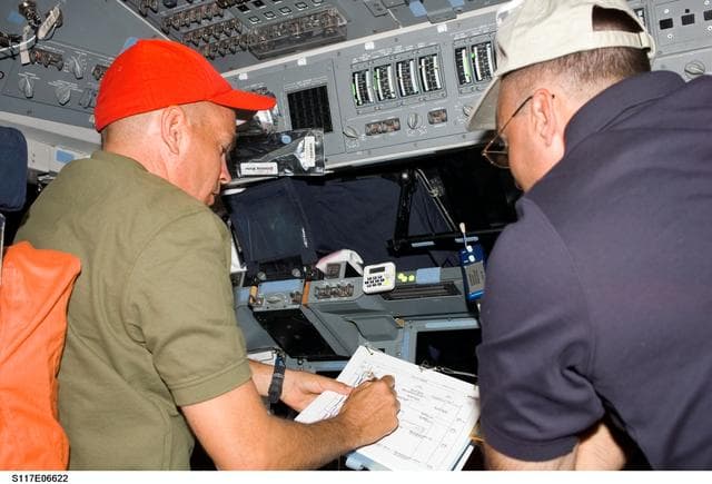 NASA image: Sturckow and Archambault look over checklists on the FD of STS-117 Space Shuttle Atlantis